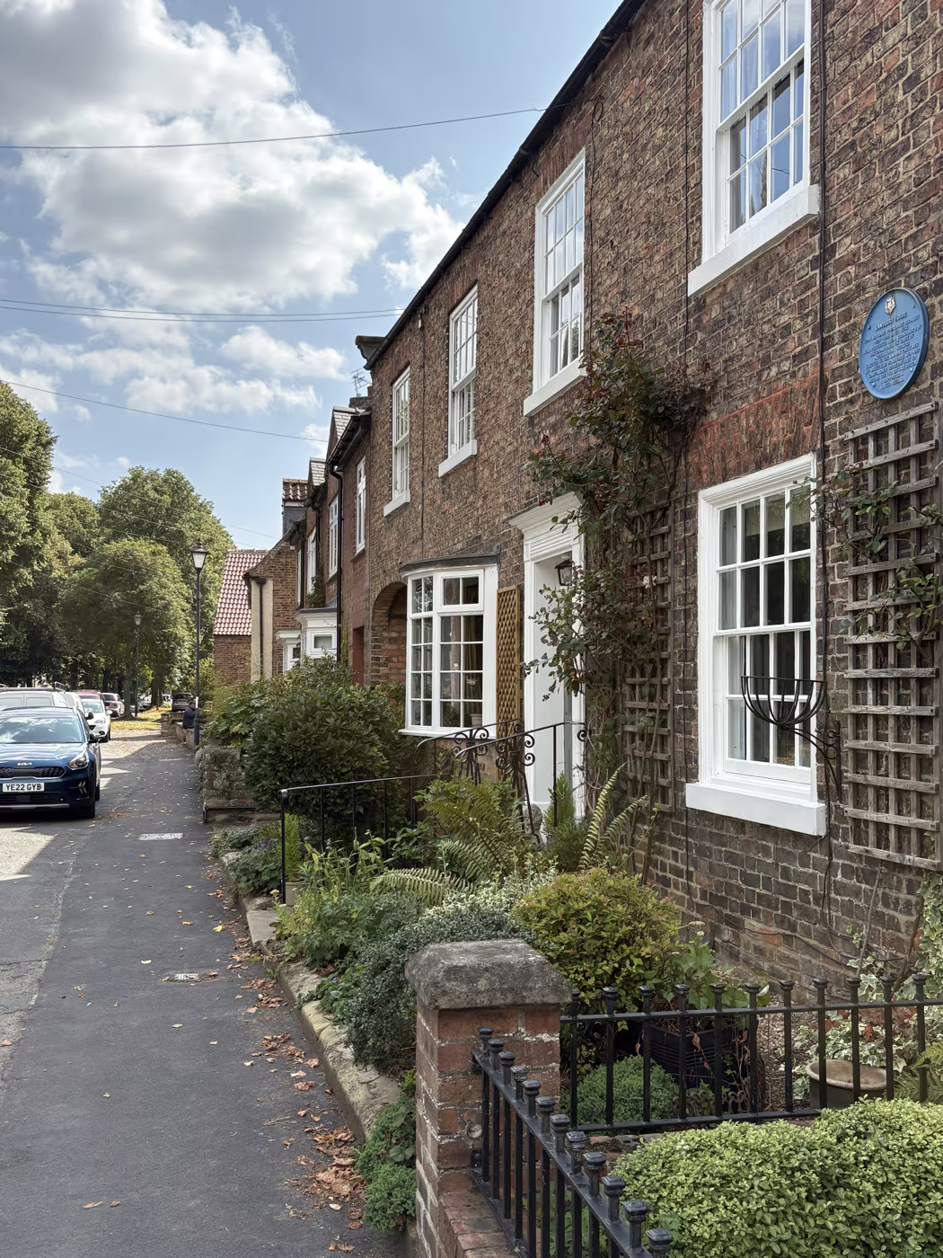The brick terrace the Hannah Packer plaque is fixed to, with front gardens, iron railings and a tree-lined verge along the street