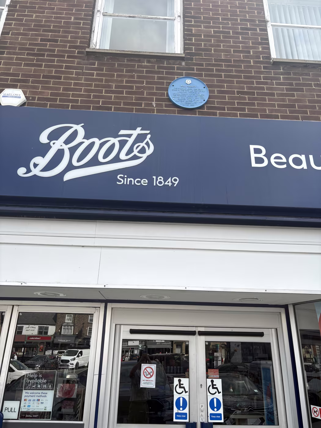 The Boots shopfront on Thirsk Market Place, the blue plaque visible on the brickwork above the fascia