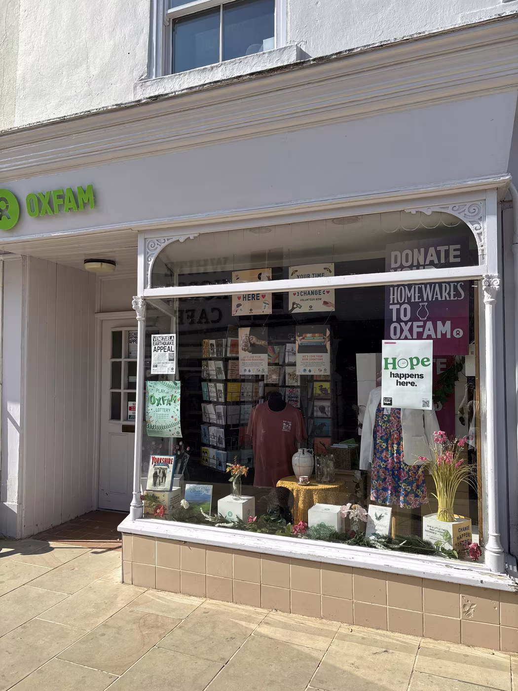 The Oxfam shop window dressed with homewares and books, with the donate sign on the door