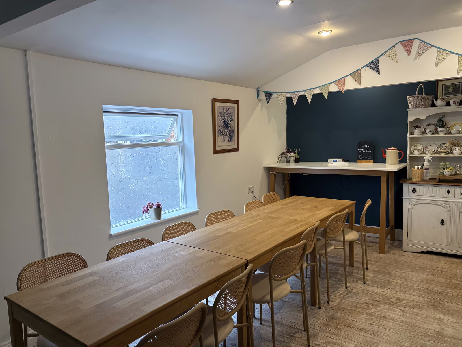 The long table upstairs at Tea Time laid out for a meeting, chairs down both sides, bunting overhead and a sash window at the end
