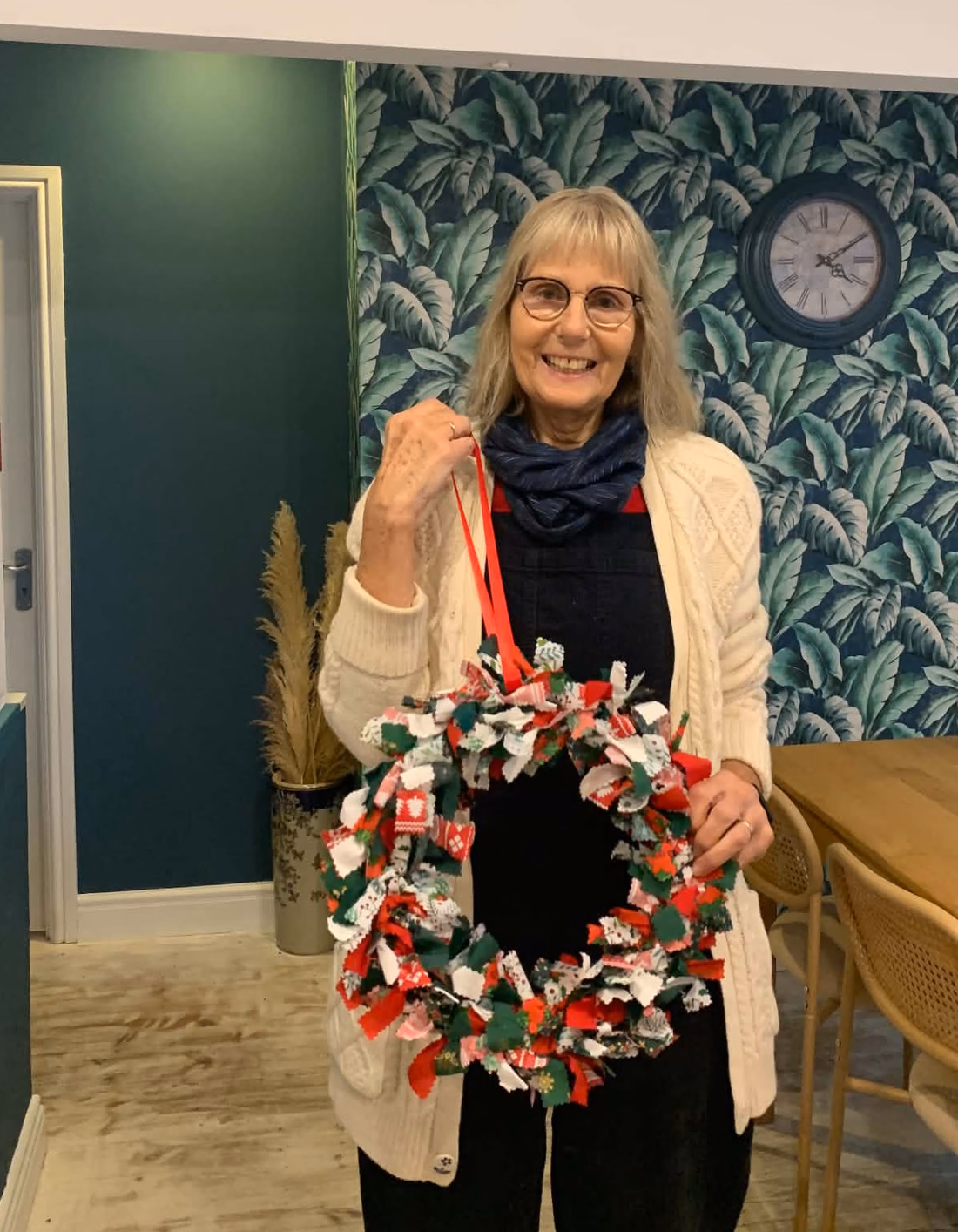 Helen Shakespeare holding a rag wreath made from red, green and white fabric