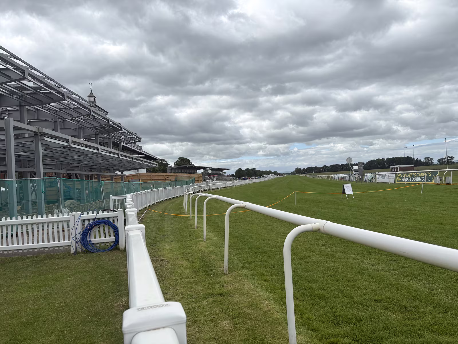 The white running rail curving away in front of the grandstand at Thirsk Racecourse on a quiet day