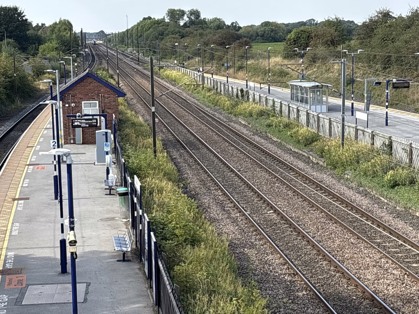 Thirsk station's platforms and the East Coast Main Line from the footbridge, with shelters on both sides