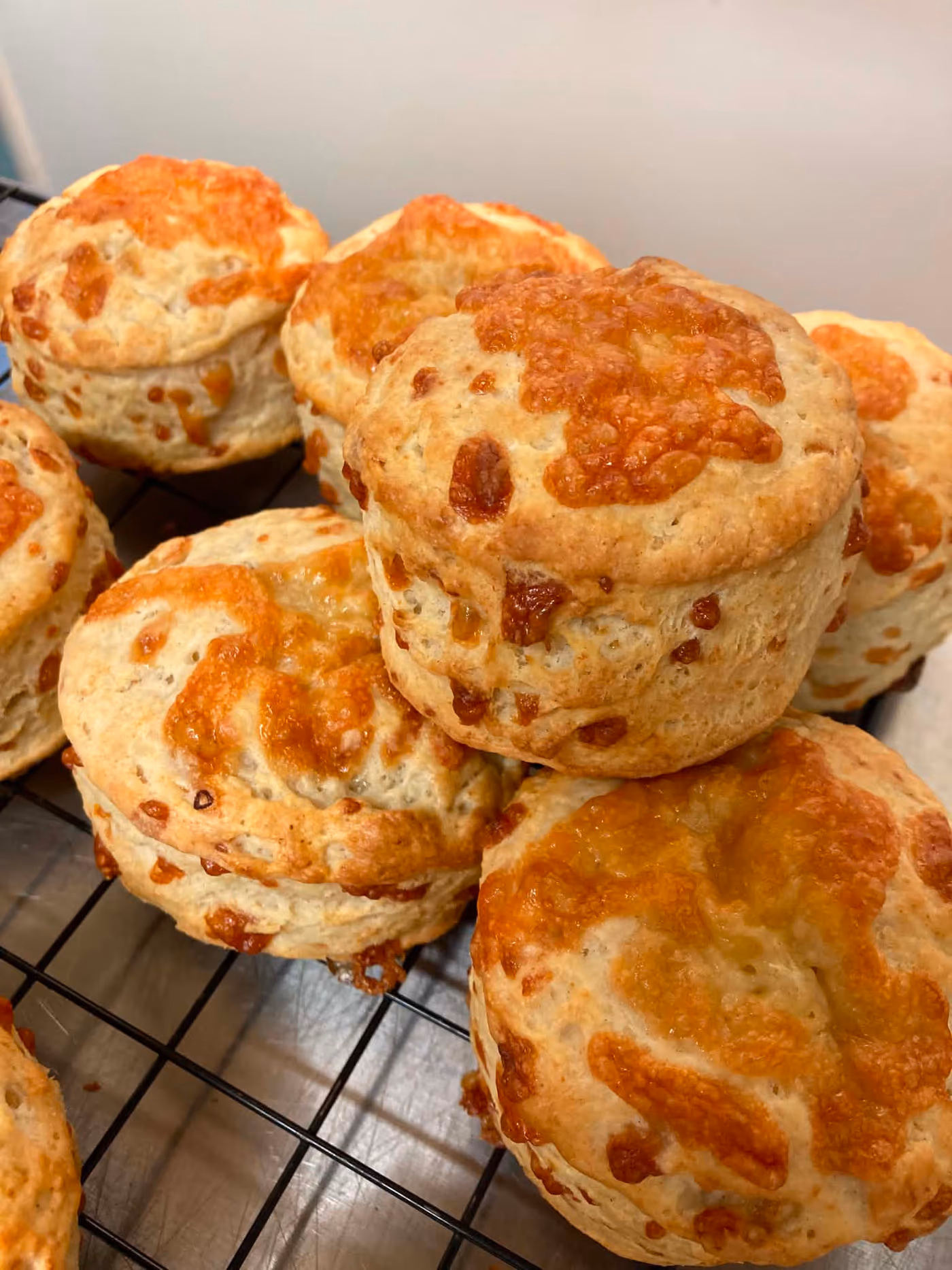 Cheese scones cooling on a rack, cheese browned and bubbling on top