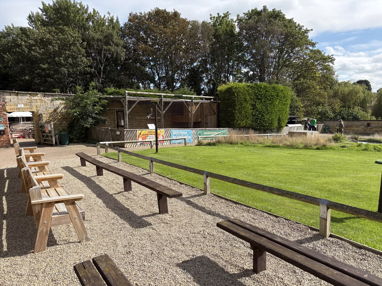 Benches and garden chairs set right along the rail of the flying ground, with the aviaries and the old garden walls behind