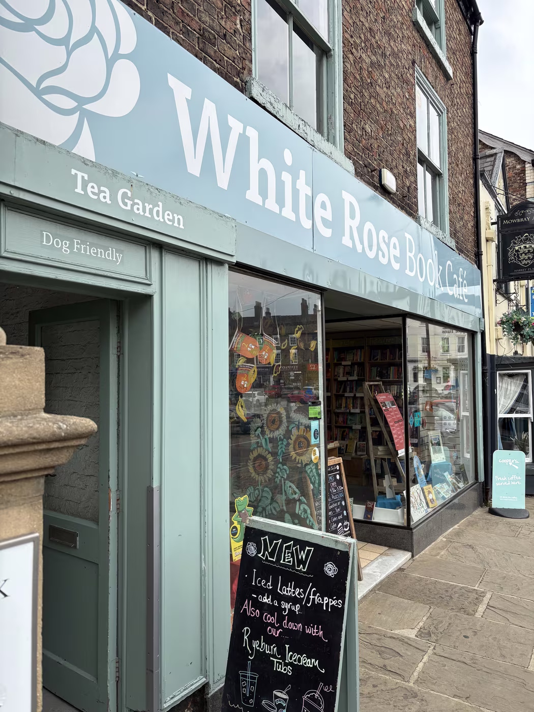 The corner of the White Rose Book Cafe on the flagged pavement, its Tea Garden and Dog Friendly signs by the door